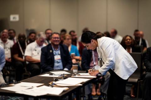 Person in room of people writing on paper